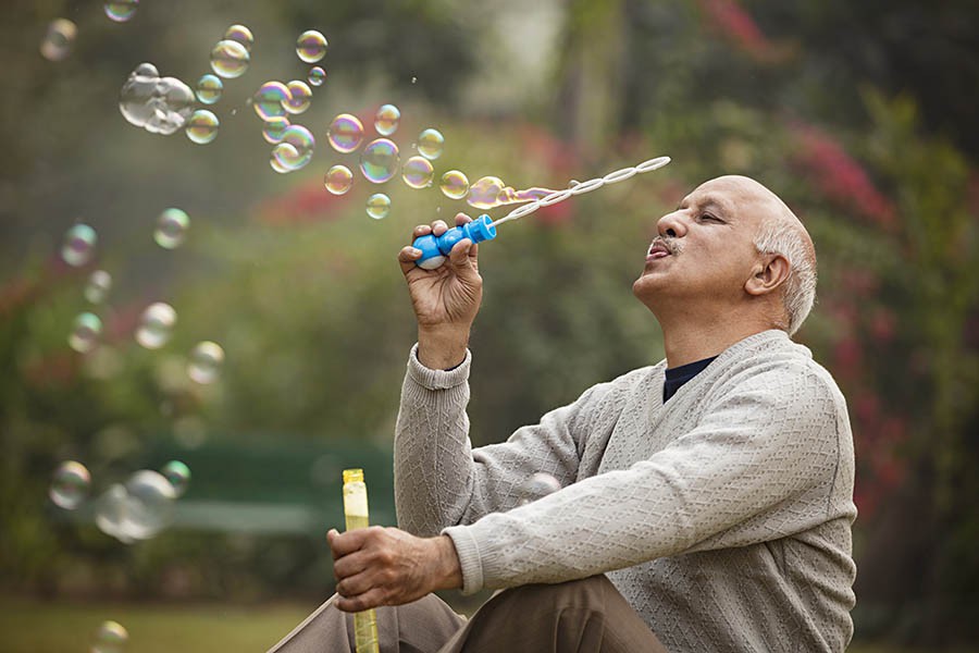 An elderly man blowing bubbles